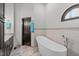 Bathroom featuring a modern freestanding tub, granite vanity, travertine tile, and framed half-moon window at 502 Hillcrest Rd, Apex, NC 27502