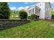 Landscaped backyard with retaining wall, green grass, shrubbery, and partial home view at 508 Morning Oaks Dr, Holly Springs, NC 27540