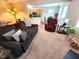 A living room featuring a sofa, recliner, piano, and a view into the adjacent kitchen at 5126 Thornton Knoll Way, Raleigh, NC 27616