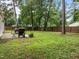 Well-maintained backyard featuring a patio, grill, seating, mature trees, and a fenced perimeter at 5801 Hadrian Dr, Durham, NC 27703