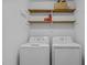 Clean laundry room with a washer, dryer, and shelving for supplies at 5801 Hadrian Dr, Durham, NC 27703