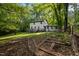 View of backyard, patio and garden boxes of a two-story home surrounded by mature trees at 6817 Guess Rd, Hillsborough, NC 27278