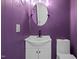 Stylish purple bathroom with a modern vanity, oval mirror, and bright lighting at 6817 Guess Rd, Hillsborough, NC 27278