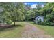 A gravel driveway leads to a charming white outbuilding surrounded by lush trees at 705 Wilsons Mills Rd, Smithfield, NC 27577