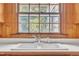 Close up of the kitchen sink and window in a knotty pine-walled kitchen at 705 Wilsons Mills Rd, Smithfield, NC 27577