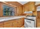 Close up of a well lit kitchen, featuring pine cabinets, white countertops, and classic white range at 705 Wilsons Mills Rd, Smithfield, NC 27577