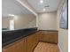 Basement wet bar with sink, wooden cabinets, black countertops, and classic tile flooring at 8909 Wellsley Way, Raleigh, NC 27613