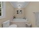 Bathroom featuring a soaking tub with a decorative chandelier and artwork at 8909 Wellsley Way, Raleigh, NC 27613