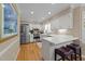 Well-lit kitchen with modern stainless steel appliances, white cabinets, and a breakfast bar with seating at 8909 Wellsley Way, Raleigh, NC 27613