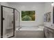 Bright bathroom featuring a shower and soaking tub with a window looking into a private green space at 901 Tamaras Cir, Wake Forest, NC 27587