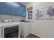 Clean laundry room featuring blue cabinets, washer, and dryer with natural light at 901 Tamaras Cir, Wake Forest, NC 27587