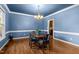 Light-filled dining room features blue walls, hardwood floors, white trim, and a chandelier at 1 Gatesway Ct, Durham, NC 27707
