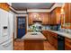 Cozy kitchen featuring wood cabinetry, a central island, and bright blue backsplash at 1 Gatesway Ct, Durham, NC 27707
