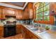 Kitchen with wood cabinets, tiled backsplash, stainless steel sink and views through a large window at 1 Gatesway Ct, Durham, NC 27707