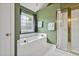 Main bathroom with jacuzzi tub, shower, window, and white tile floors and green walls at 100 Highfield Ave, Cary, NC 27519
