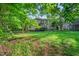 Spacious backyard with mature trees, green grass, and view of the rear of the house at 105 Walter Hagen Dr, Mebane, NC 27302