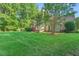 Well-maintained backyard with mature trees, green grass, and a glimpse of the house at 105 Walter Hagen Dr, Mebane, NC 27302