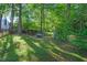 Secluded backyard featuring a stone patio area, green grass, mature trees, and landscaping at 105 Walter Hagen Dr, Mebane, NC 27302