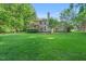 Lush green backyard with mature trees, landscaping, a deck, and a view of the house at 105 Walter Hagen Dr, Mebane, NC 27302
