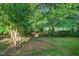 Landscaped backyard featuring a mix of grass, shrubs, mature trees, and mulched beds at 105 Walter Hagen Dr, Mebane, NC 27302