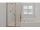 Bright bathroom featuring a tub and shower with glass enclosure and window at 117 Drakewood Pl, Cary, NC 27518
