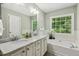 Bright bathroom featuring double sinks with marble countertops, modern fixtures, bathtub and window at 12620 Waterlow Park Ln, Raleigh, NC 27614