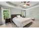 Well-lit bedroom with ceiling fan, decorative quote on the wall, and view of trees through the windows at 12620 Waterlow Park Ln, Raleigh, NC 27614