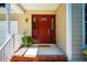 Covered front porch featuring a red front door, decorative sidelights, and brick-lined landing with a potted plant at 13 Boxwood Dr, Durham, NC 27713