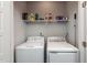 Bright laundry room features white washer and dryer, a shelf with laundry supplies, and white walls at 1363 Brown Velvet Ln, Apex, NC 27523