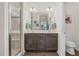 Bright bathroom with double sink vanity, a large mirror, and a glass-enclosed shower at 1409 Sage Tree Dr, Zebulon, NC 27597