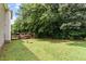 Spacious backyard featuring a wooden deck, swing set, and lush green lawn surrounded by mature trees at 161 Jacob St, Holly Springs, NC 27540