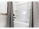 A clean, well-lit white bathtub with updated black fixtures and a grey shower curtain at 1626 Plover Cir, Fuquay Varina, NC 27526