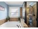 Bright bathroom featuring a soaking tub with tile surround and a glass-enclosed shower with bronze fixtures at 2027 River Grove Ln, Knightdale, NC 27545