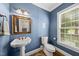 Charming powder room with blue walls, pedestal sink, and natural light from the window at 2027 River Grove Ln, Knightdale, NC 27545