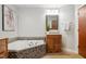 Bright bathroom featuring a soaking tub with mosaic tile surround and wooden vanities at 205 Northfield Dr, Raleigh, NC 27609