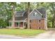 View of home's full yard and two-story elevation featuring brick facade, gray siding, and inviting covered front porch at 205 Northfield Dr, Raleigh, NC 27609