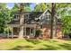 Charming two-story home featuring a brick facade, gray siding, and inviting front porch nestled among mature trees at 205 Northfield Dr, Raleigh, NC 27609