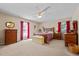Main bedroom with furniture, carpet flooring, ceiling fan and two windows with red drapes at 2257 Delaney Dr, Burlington, NC 27215