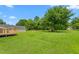 Expansive backyard with lush lawn, mature trees, and a wooden deck on the rear of the house at 232 S Marshall St, Graham, NC 27253