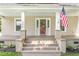 Inviting front porch with sturdy white columns, an American flag, and a freshly painted red front door at 232 S Marshall St, Graham, NC 27253