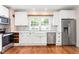 White cabinets, stainless steel appliances, and a farmhouse sink add charm to this renovated kitchen at 232 S Marshall St, Graham, NC 27253