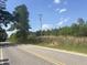 View of paved road next to grassy shoulder dotted with lush green trees and vegetation at 248-A Gilbert Rd, Benson, NC 27504