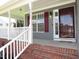 Inviting front porch features classic white railings, brick steps, and a storm door entrance with burgundy shutters at 2662 Walas Ct, Creedmoor, NC 27522
