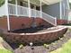Beautifully landscaped front yard with a brick retaining wall, lush greenery, and a charming lawn at 2662 Walas Ct, Creedmoor, NC 27522