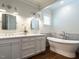 Bathroom with a double sink vanity, marble countertops, soaking tub and white cabinets at 300 W Roanoke Park Dr, Raleigh, NC 27608