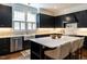Modern kitchen features navy cabinets, marble counters, stainless steel appliances, and island seating at 300 W Roanoke Park Dr, Raleigh, NC 27608