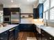 Modern kitchen features navy cabinets, marble counters, stainless steel appliances, and floating wood shelves at 300 W Roanoke Park Dr, Raleigh, NC 27608
