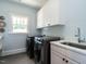 Well-lit laundry room with front loading washer and dryer and ample cabinet space at 300 W Roanoke Park Dr, Raleigh, NC 27608