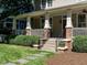 The cozy front porch features brick detailing, white columns, and well-maintained landscaping at 300 W Roanoke Park Dr, Raleigh, NC 27608