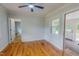 Cozy bedroom with hardwood floors, neutral paint, a ceiling fan, and access to the sunroom at 303 Winhaven St, Roxboro, NC 27573